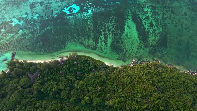Aerial view of a lush tropical coastline with turquoise waters and dense green vegetation in Baie Ste Anne, Baie Sainte Anne, Seychelles.