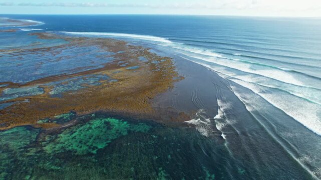 Aerial drone footage of the reef in Lakey beach surfing famous spot in Dompu regency, Sumbawa island, Indonesia, with corals, long waves with blue turquoise  water, sunny weather