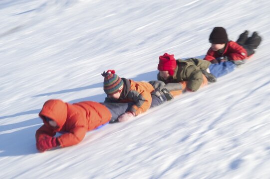 Chain of children sliding on their bellies downhill