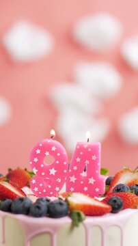 Birthday cake candle number 94. Vertical video of candle and cake on pink background and fire by lighter. Close-up and slow motion