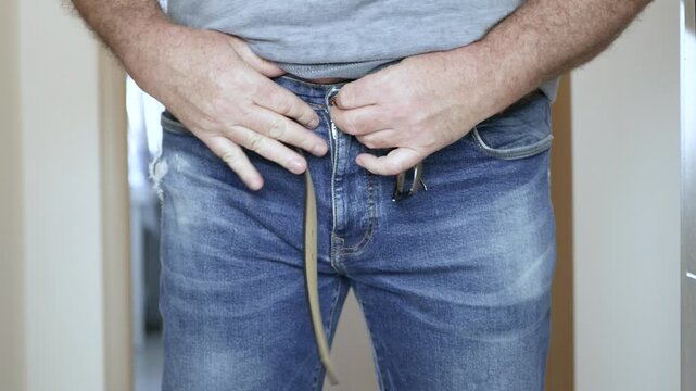 Overweight Man Struggling to Fasten Belt on Jeans Closeup. Man with Big Belly Trying to Buckle Leather Belt.