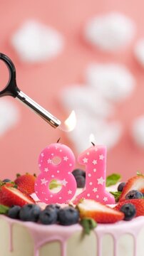 Birthday cake candle number 81. Vertical video of candle and cake on pink background and fire by lighter. Close-up and slow motion
