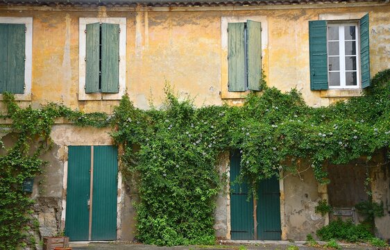 Traditional Proven&ccedil;al style clay built house facade with a faded stucco wall and the typical green wooden window shutters in Aubagne, Bouches-du-Rh&ocirc;ne, Provence France.