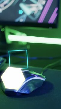 Vertical video: After pause neon shapes appearing rotating over wired gaming mouse boosting glow