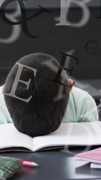 Vertical video: Boy reading, lowering head on school book from tired, letters overlaying foreground