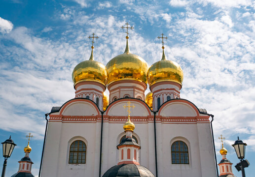 Majestic Assumption Cathedral at Valdai Iversky Monastery showcasing golden onion domes under a bright cloudy sky