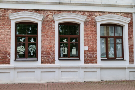 Three windows with brown frames on red brick building facade