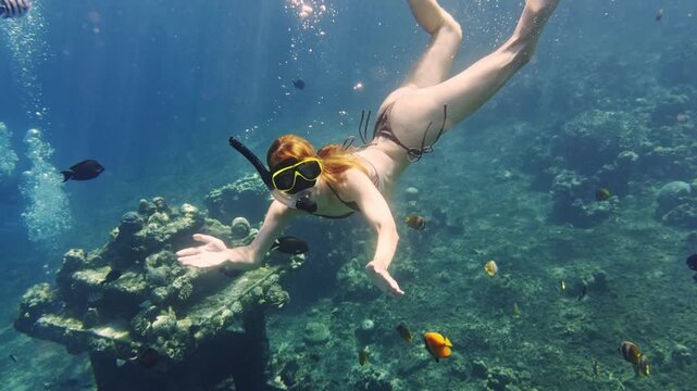 Woman freediving and snorkeling with tropical fish