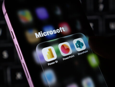 Closeup of a smartphone screen displaying microsoft mobile applications including power bi, powerpoint, and sharepoint icons