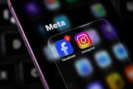 Closeup of a smartphone screen displaying the meta logo with facebook and instagram app icons, representing social media and technology