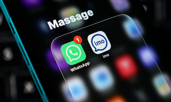 Closeup of smartphone screen showing whatsapp and imo messaging app icons with a notification badge on a dark background