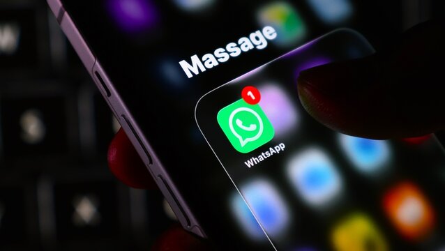 Closeup of a persons finger touching a whatsapp app icon on a smartphone screen with a notification badge