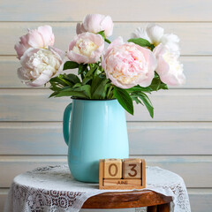 calendar blocks showing June 03 with pink and white peonies in a blue jug on a rustic table for summer holiday concept
