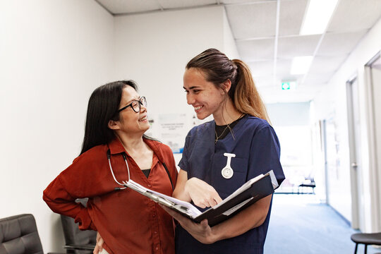 Care providers collaborating over patient records in clinic hallway
