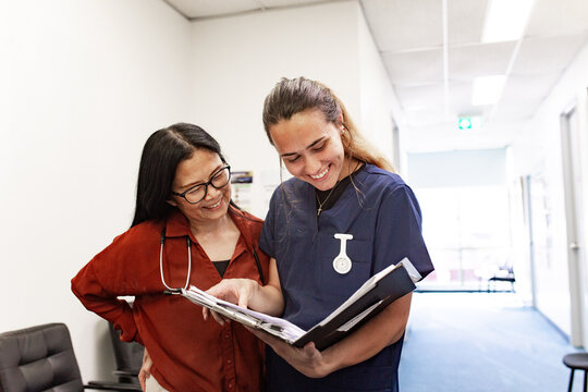 Care providers collaborating over folder in health centre hallway
