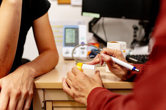 Medical doctor holding a sample specimen container talking with a patient in a clinic