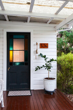 front door of country farmhouse home with sunset light through stain glass window panel