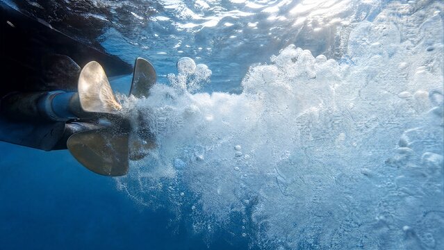 A boat propeller churning water, creating a dense cloud of white bubbles and froth.
