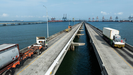 Fototapeta premium Aerial drone shot of container trucks driving to the port for cargo shipping.