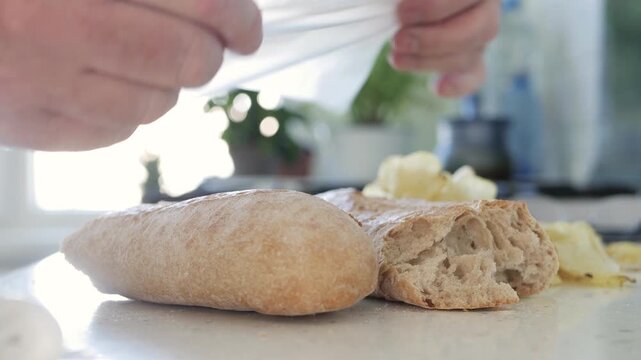 Close Up Shooting with a Hungry Person Putting Half of the Bread in a Plastic Bag for Eating Later. Food Economy Concept.