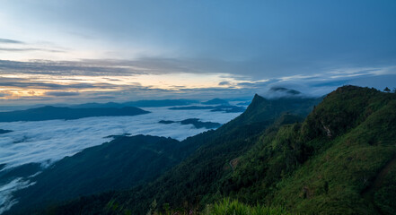 Fototapeta premium Green mountain ridge with clouds and sea of mist at sunrise, scenic natural landscape and peaceful morning.