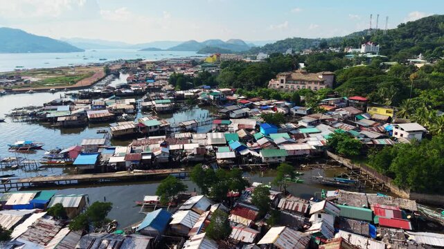 Aerial view of a coastal waterway in Coron Palawan Philippines with stilt houses small boats hillside buildings green trees and distant island water