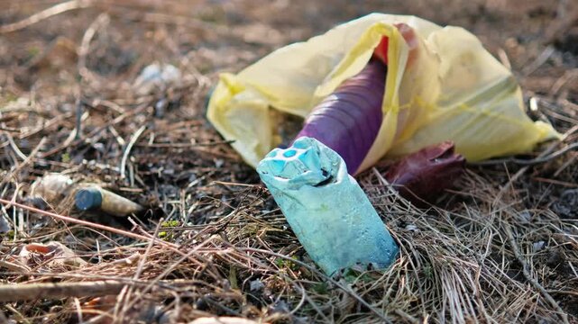 Plastic trash discarded on dry grass in nature causing environmental pollution issues and ecological damage to wilderness habitat.