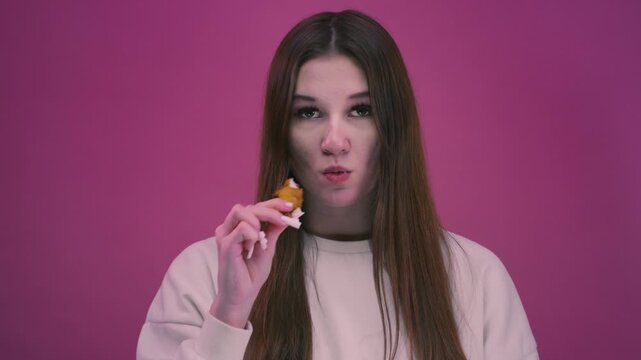 Woman eating a fried chicken wing from fast food. Teen girl bites unhealthy junk. Crispy chicken pieces, takeaway food, casual dining moment. Young female have a crispy meat.