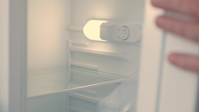 Man Hand Opens an Empty Fridge Door Looking Inside for Fresh Food and Drink. Empty Fridge, Food Crisis Concept.