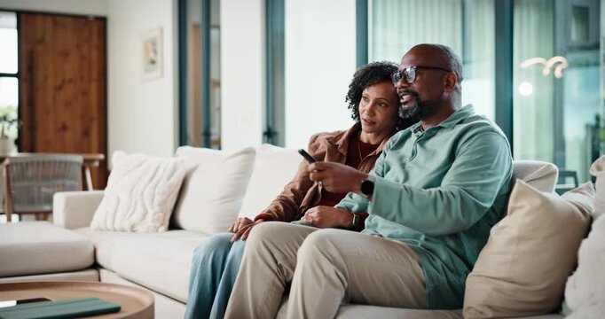 Couple, watching tv and remote on sofa with smile, choice and point with show in living room. Mature man, woman and decision with movies, television or film subscription on couch in lounge at house