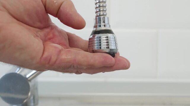 Man Checking Water Leaking and a Defective Faucet. A Hand Collecting Water Drops from a Broken Water Tap. Water Economy Concept.