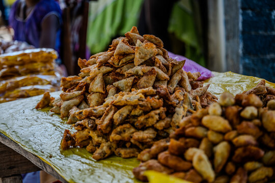 Fried samosas and street food displayed on a yellow plastic sheet at a market in Ranomafana