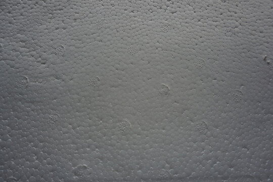 Macro shot of a white expanded polystyrene foam surface, showing the detailed cellular texture and structure. White plastic foam packaging material close-up.
