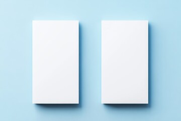 Fototapeta premium Two vertical blank white rectangular panels positioned side by side with soft shadows on a light blue background creating a clean minimal presentation mockup