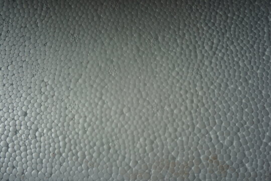 Macro shot of a white expanded polystyrene foam surface, showing the detailed cellular texture and structure. White plastic foam packaging material close-up.
