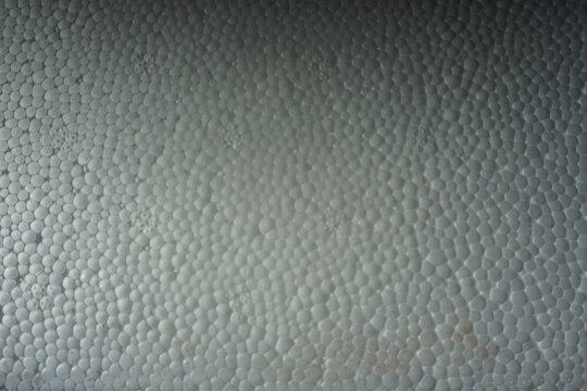 Macro shot of a white expanded polystyrene foam surface, showing the detailed cellular texture and structure. White plastic foam packaging material close-up.
