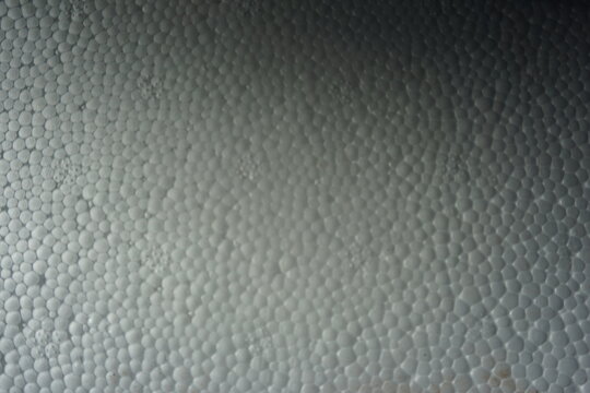 Macro shot of a white expanded polystyrene foam surface, showing the detailed cellular texture and structure. White plastic foam packaging material close-up.