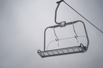 Fototapeta premium Empty ski chairlift number 67 hanging against gray overcast sky
