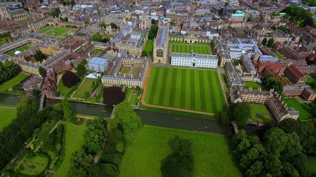 4K aerial view of King's College Chapel, Gibbs Building and striped front court lawn at Cambridge University with punts gliding on the River Cam through The Backs.
