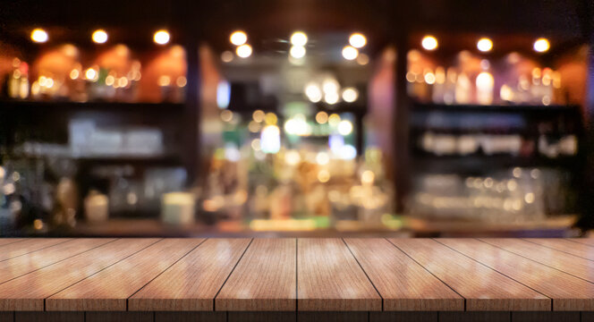 Empty wooden table top with lights bokeh on blur restaurant background.