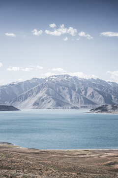 Landscape in the Pamir Mountains with a blue lake Yashilkul in the Tien Shan, a panoramic view of the highlands with snow-capped rocky peaks and the blue waters of the lake