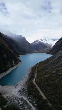 Huaraz, Peru: Forward footage of famous laguna paron in Caraz, Huaraz region, Peru. Surrounded by mountain range and with cloudy dramatic sky, showing cordillera blanca in the background