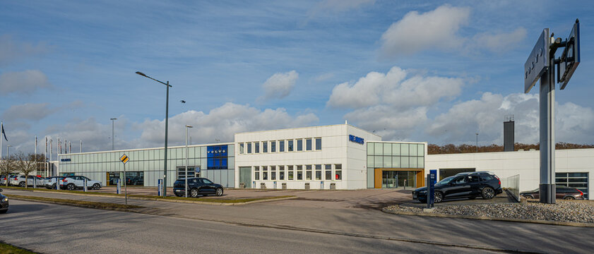 Falkenberg, Sweden - March 28 2026: Modern car dealership exterior with showroom building and parking area under blue sky.