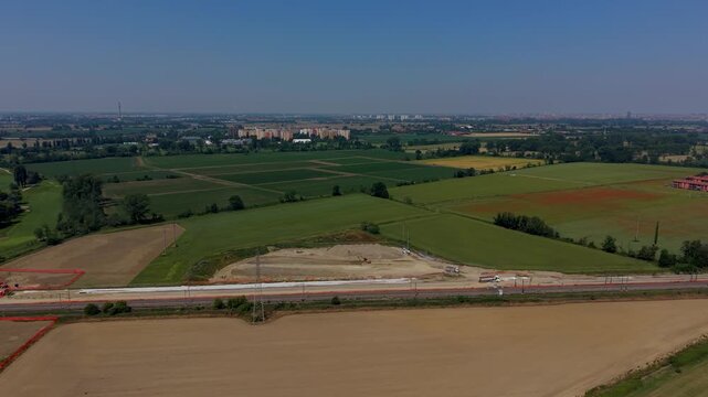 Rural Landscape Construction: An aerial view captures the ongoing development of a new railway line cutting through a vast, fertile agricultural landscape.