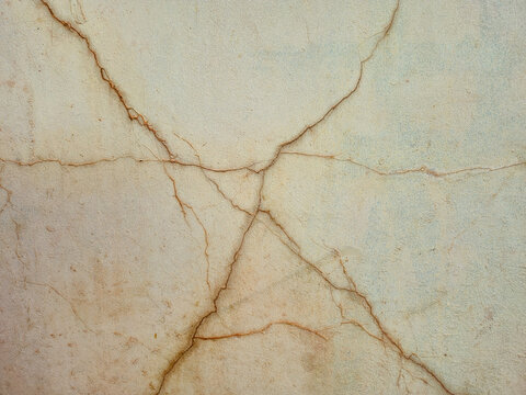 Cracked concrete wall background with texture, damaged stucco surface with deep fractures, close-up of old weathered cement wall backdrop for design