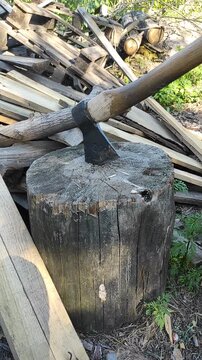 Old axe with wooden handle sharpened in a wooden log against a background of old and new boards
