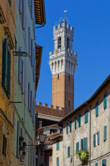 Fototapeta premium SIENA, ITALY, April 25, 2026 : Torre del Mangia of Palazzo Pubblico can be seen from the small streets of city center