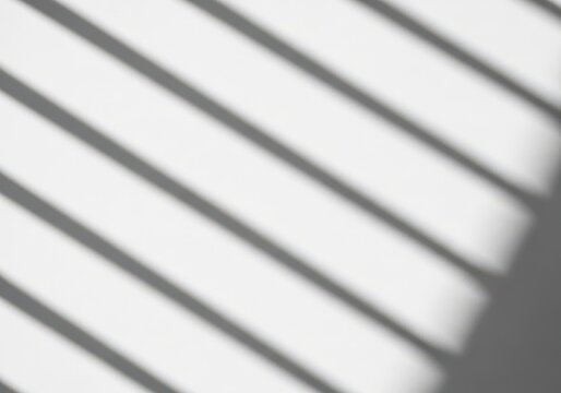 Shadows of window blinds casting diagonal stripes on white wall background.