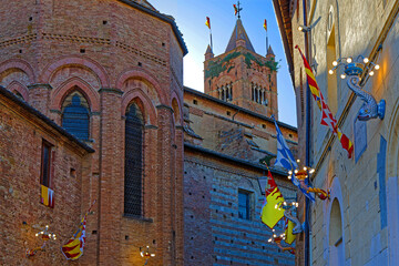 Fototapeta premium SIENA, ITALY, April 24, 2026 : San Clemente in Santa Maria dei Servi and a small street decorated with flags