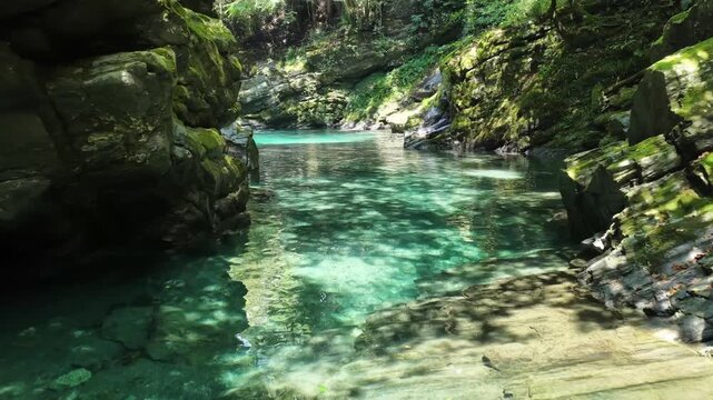 Low aerial drone flight along emerald green stream toward Kamitodoroki Falls in Kochi Japan

